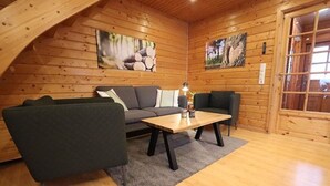 Tunnelmallinen huone, jossa on puuseinät, sohva, sohvapöytä ja matto.