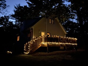Une maison dotée d’une terrasse et d’un escalier en bois, entourée d’arbres.