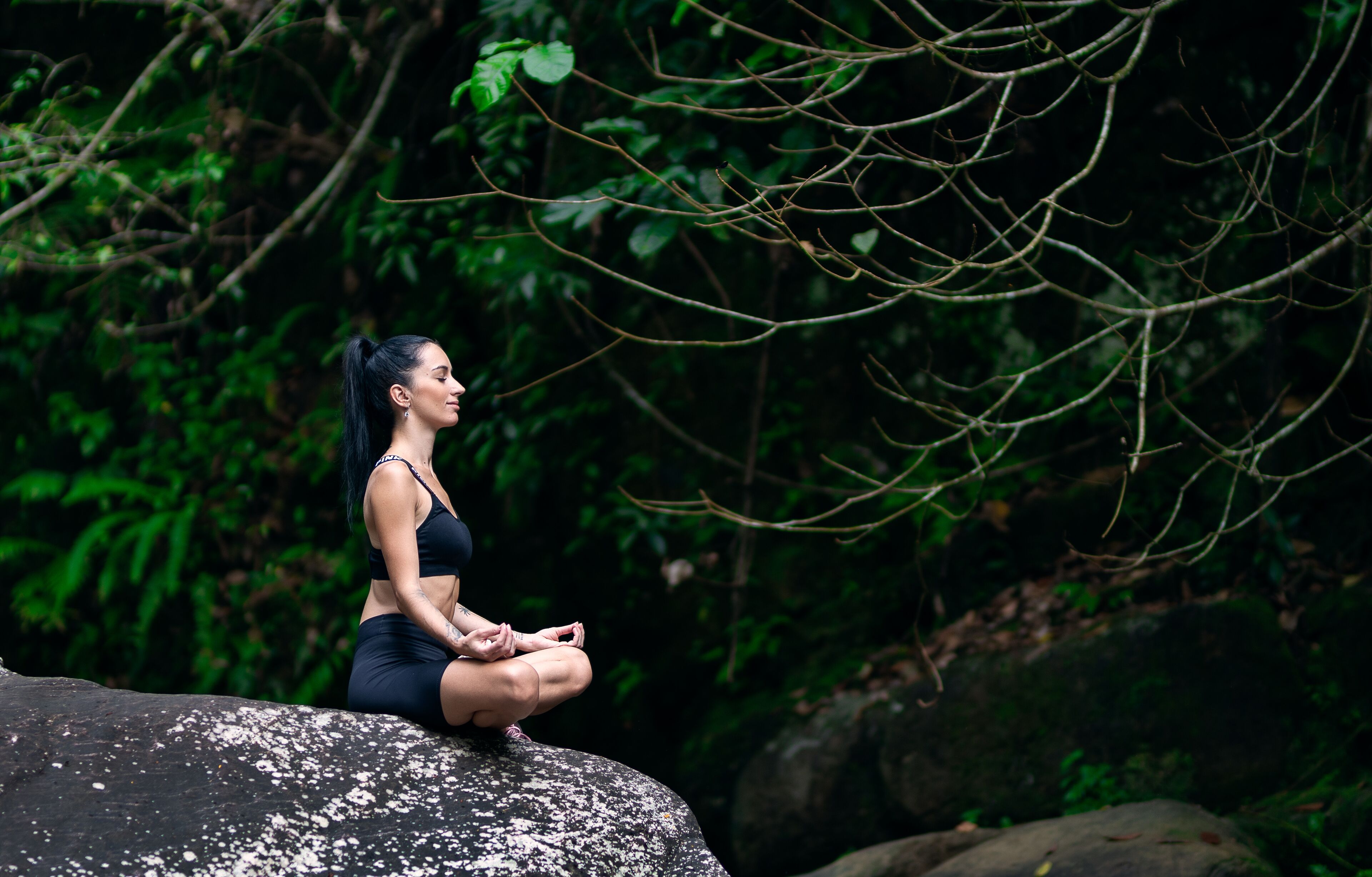 A person sitting on a rock in a natural setting.
