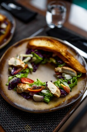 A plate with a salad and a grilled chicken sandwich.