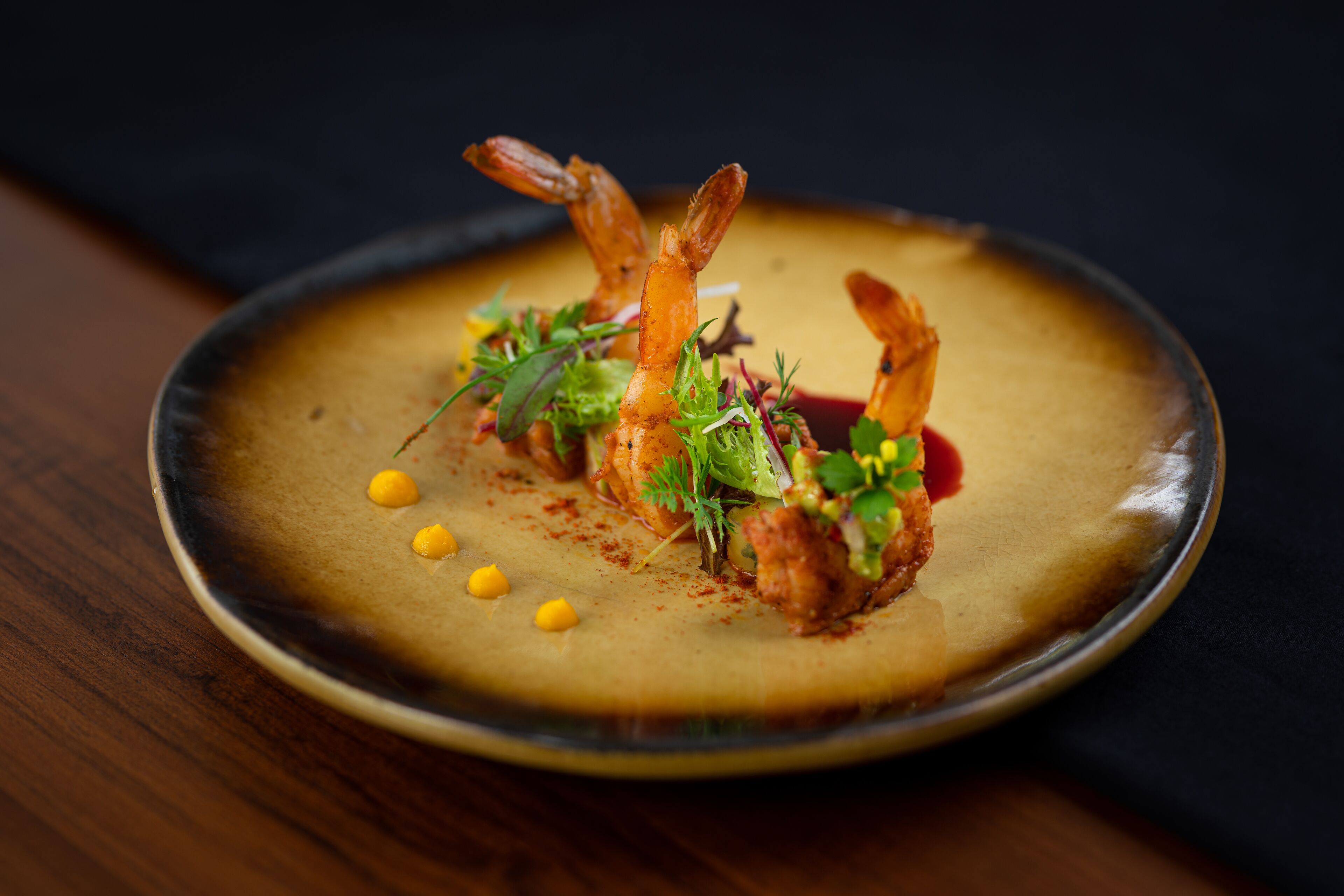 Un plato de comida con camarones y verduras sobre un plato oscuro.