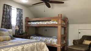 Una habitación con una cama litera, un escritorio con lámpara, una silla y un ventilador de techo.