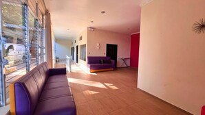 A spacious living area with a purple sofa, a smaller couch, and a dining table. - Quinta Sunset - Coatepeque Lake (El Congo)