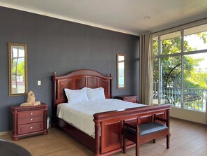 A bedroom with a large bed, a nightstand, a bench, and two mirrors on the wall. - Quinta Sunset - Coatepeque Lake (El Congo)