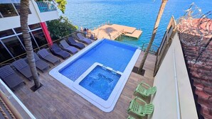 A rooftop pool with a hot tub, lounge chairs, and a view of the sea. - Quinta Sunset - Coatepeque Lake (El Congo)