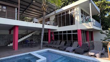 A two-story building with a swimming pool, outdoor seating, and a staircase.