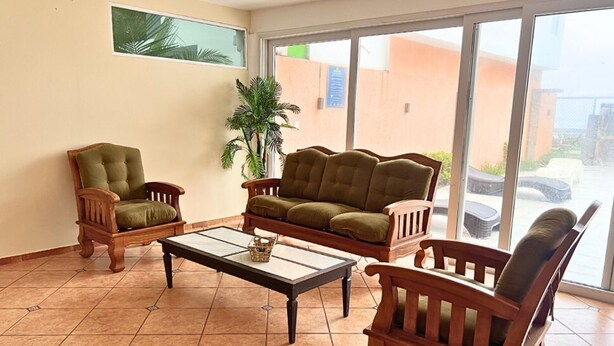 Un salon comprenant un canapé, deux fauteuils, une table basse et une plante en pot.