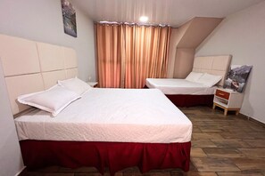 Una habitación con dos camas, piso de madera y un cuadro en la pared.