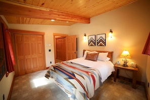 A bedroom with a bed, wooden wardrobe, and a nightstand with a lamp.