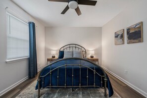 Ein Schlafzimmer mit einem gewölbten Bett, Nachttischlampen, einem Deckenventilator und zwei Bildern an der Wand.
