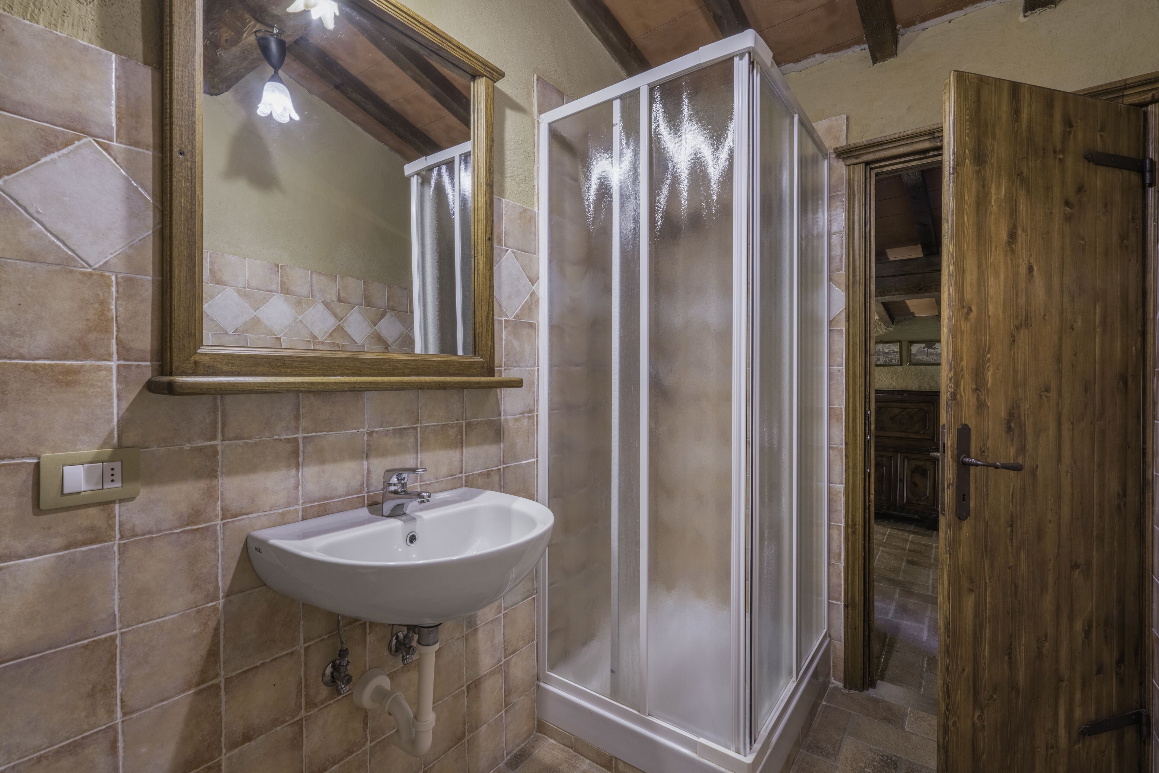 A bathroom with a white sink, a mirror, and a glass shower enclosure.