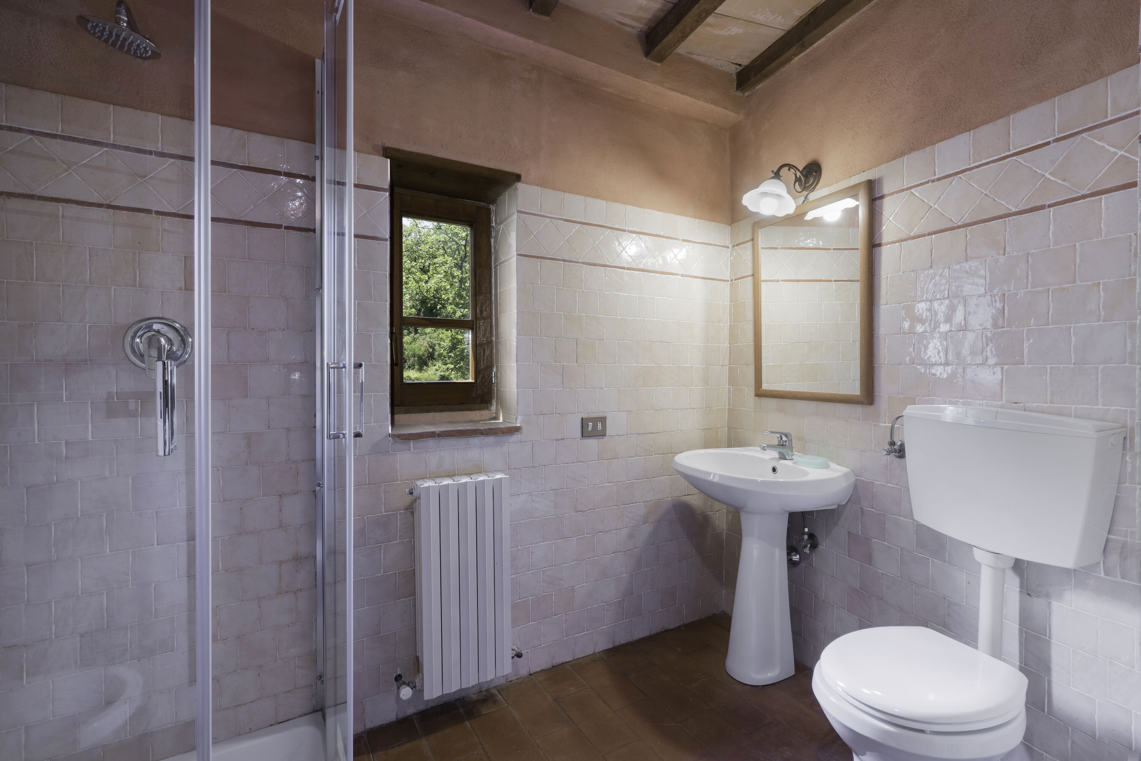 A bathroom with a glass-enclosed shower, a pedestal sink, and a toilet.