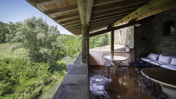 Eine überdachte Terrasse mit einer Steinwand, einem Tisch und Stühlen.