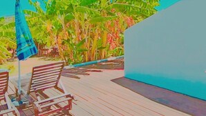 A wooden deck with lounge chairs and a blue umbrella, surrounded by lush greenery. - Fully furnished tranquil apartment in Zakynthos (Lithakia)