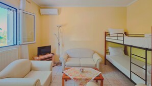A compact room with a bunk bed, a sofa, a television, and a floor lamp. - Fully furnished tranquil apartment in Zakynthos (Lithakia)