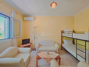 A compact room with a bunk bed, a sofa, a television, and a floor lamp. - Fully furnished tranquil apartment in Zakynthos (Lithakia)