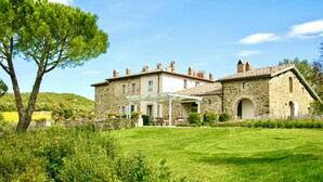 Un bâtiment en pierre doté d’un patio couvert et d’une pelouse.