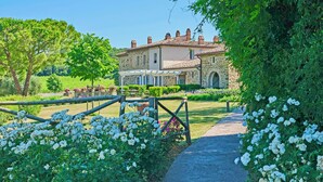 Un bâtiment en pierre avec un jardin et un chemin qui y mène.