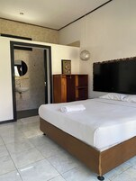 Un dormitorio con cama, armario de madera, baño con lavamanos y espejo.