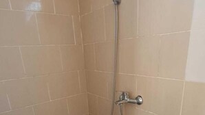 A small, tiled shower room with a showerhead and faucet.