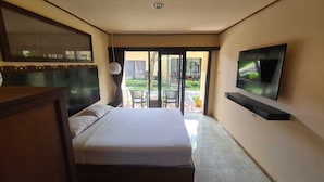 A bedroom with a bed, a TV mounted on the wall, and a sliding glass door leading to an outdoor area.