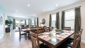 A spacious dining area with a large table set for six, surrounded by wooden chairs. - Modern|Spacious|10br|Sleeps 20|10mintoDisney|PrivatePool|Villa (Kissimmee)
