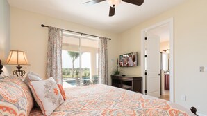 A bedroom with a large bed, a ceiling fan, a TV on the wall, and a view of the outdoors. - Modern|Spacious|10br|Sleeps 20|10mintoDisney|PrivatePool|Villa (Kissimmee)