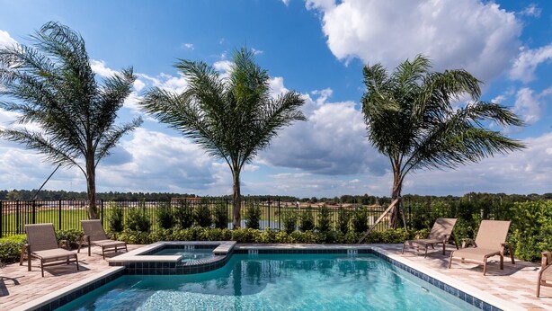 A swimming pool with lounge chairs and a hot tub, surrounded by palm trees and a view of a sports field. - Modern|Spacious|10br|Sleeps 20|10mintoDisney|PrivatePool|Villa (Kissimmee)