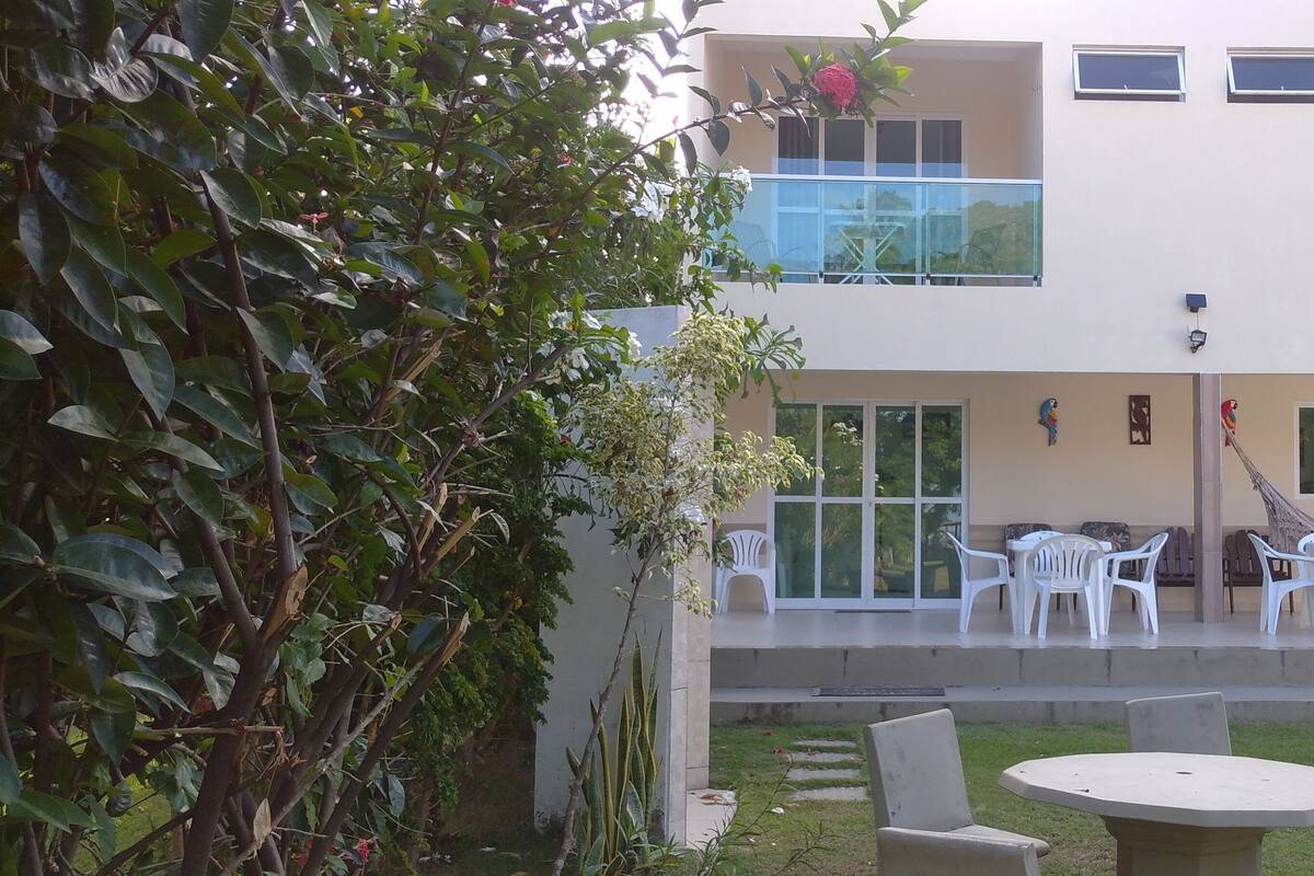 Un bâtiment à deux étages doté d’un balcon, d’un espace extérieur aménagé pour s’asseoir et d’un hamac.