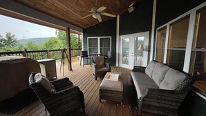 Een overdekt terras buiten met rieten meubilair, een tafel en een plafondventilator.