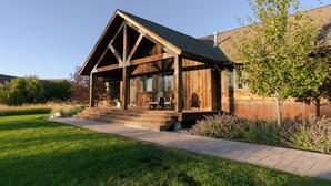 Une cabane en bois dotée d’une véranda, de grandes fenêtres et offrant une vue sur le paysage environnant.