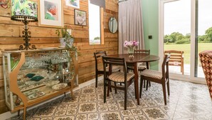 A dining area with a wooden table and chairs, a glass display cabinet, and a view of the outdoors through a sliding door. - Lulu Logs (Bristol)