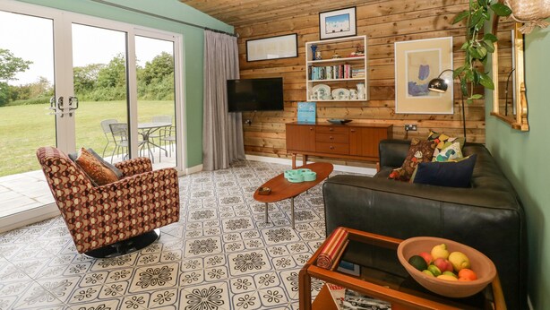 A cozy living room with a patterned sofa, a coffee table, and a bookshelf. - Lulu Logs (Bristol)
