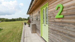 A wooden cabin with a bright green door and the number 2 on the wall. - Lulu Logs (Bristol)