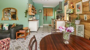 A cozy living room with a wooden ceiling, a dining table with chairs, a kitchen area with wooden cabinets, and a green wall. - Lulu Logs (Bristol)