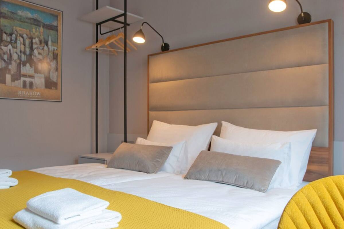 Una habitación de hotel con cama, cabecera, un cuadro en la pared y una lámpara.