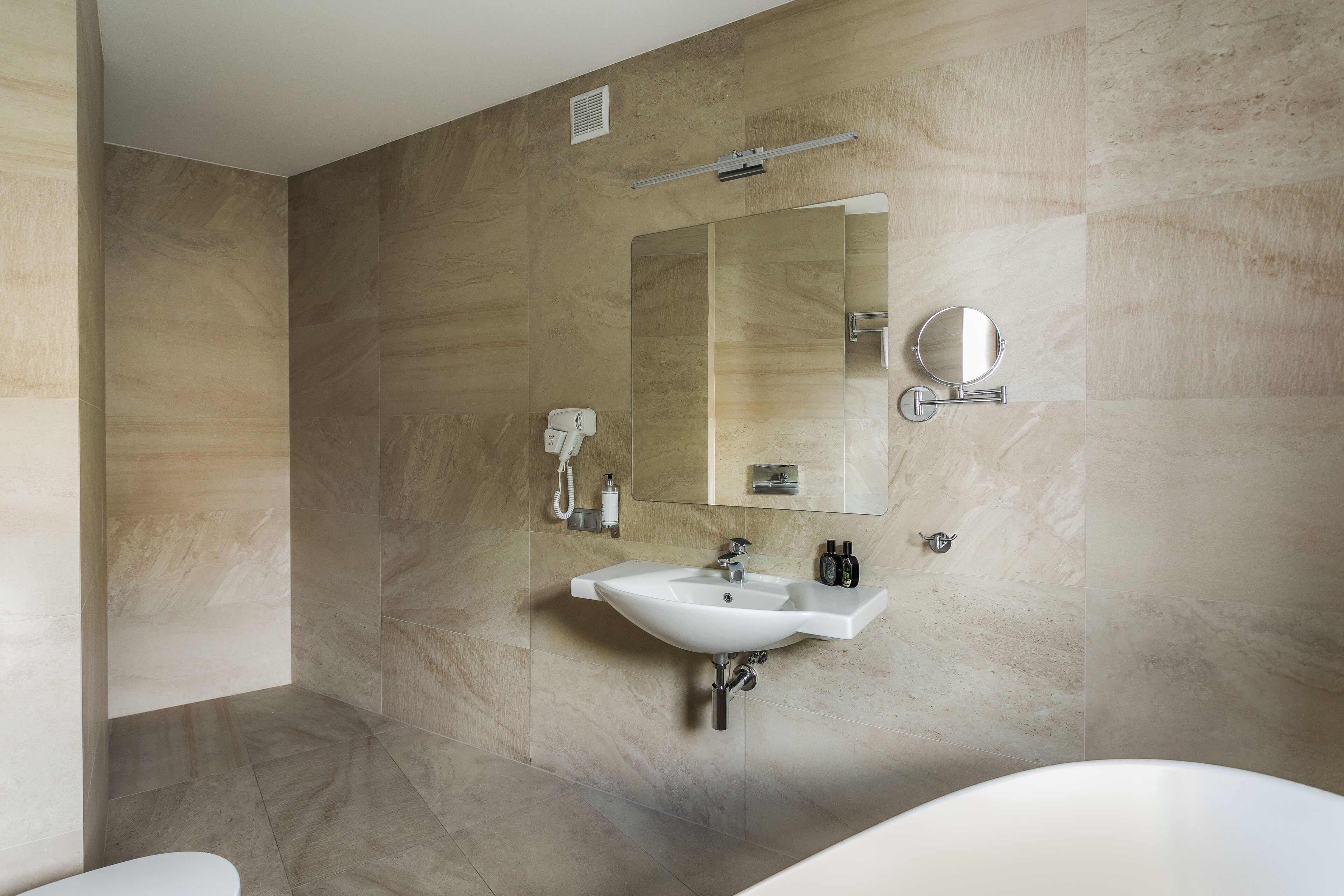 Un baño moderno con un lavamanos grande, un espejo y un cabezal de ducha manual.