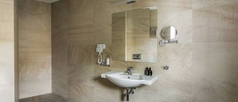 Un baño moderno con un lavamanos grande, un espejo y un cabezal de ducha manual.