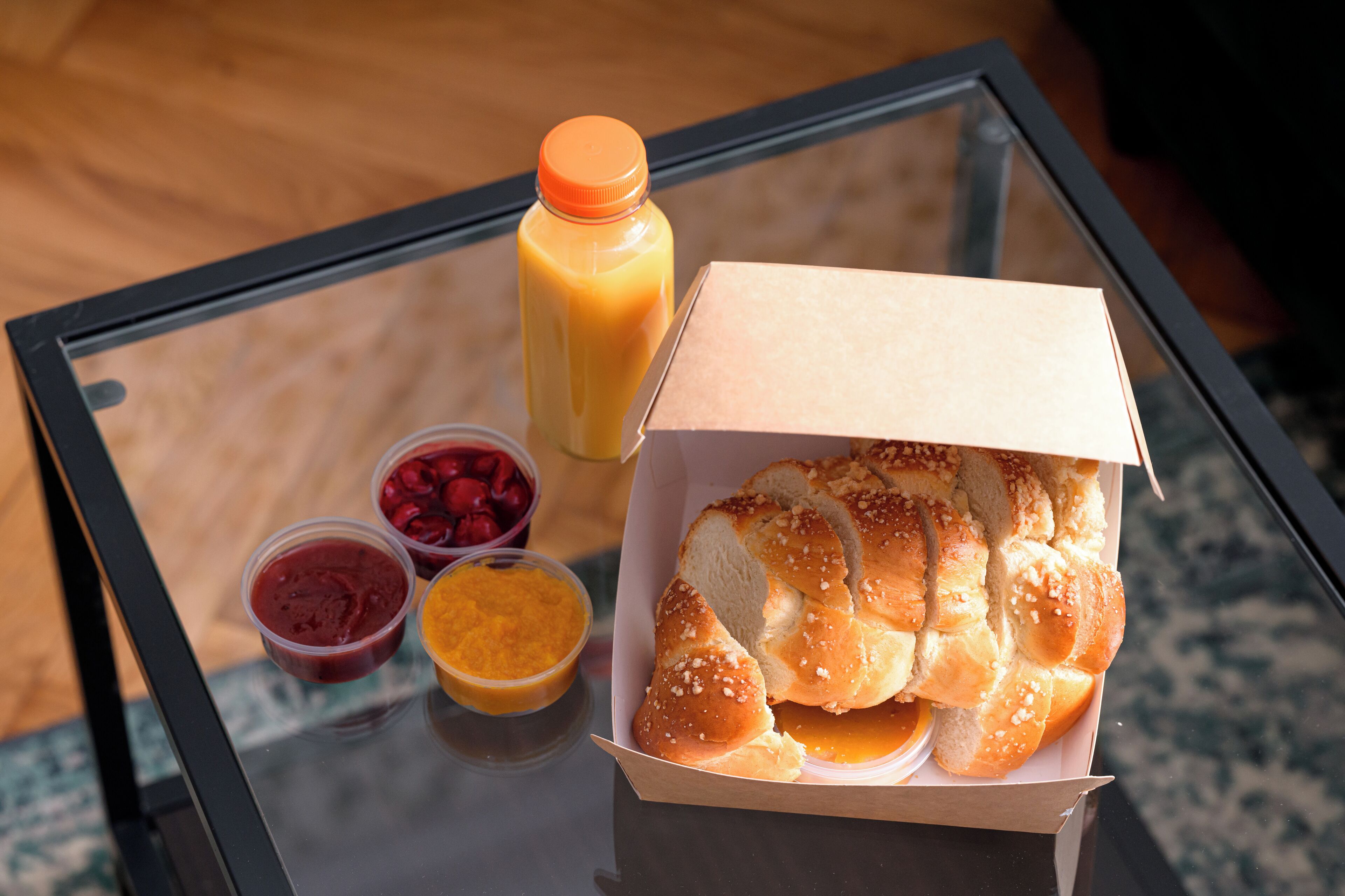 A glass table with a box of bread and a bottle of juice.