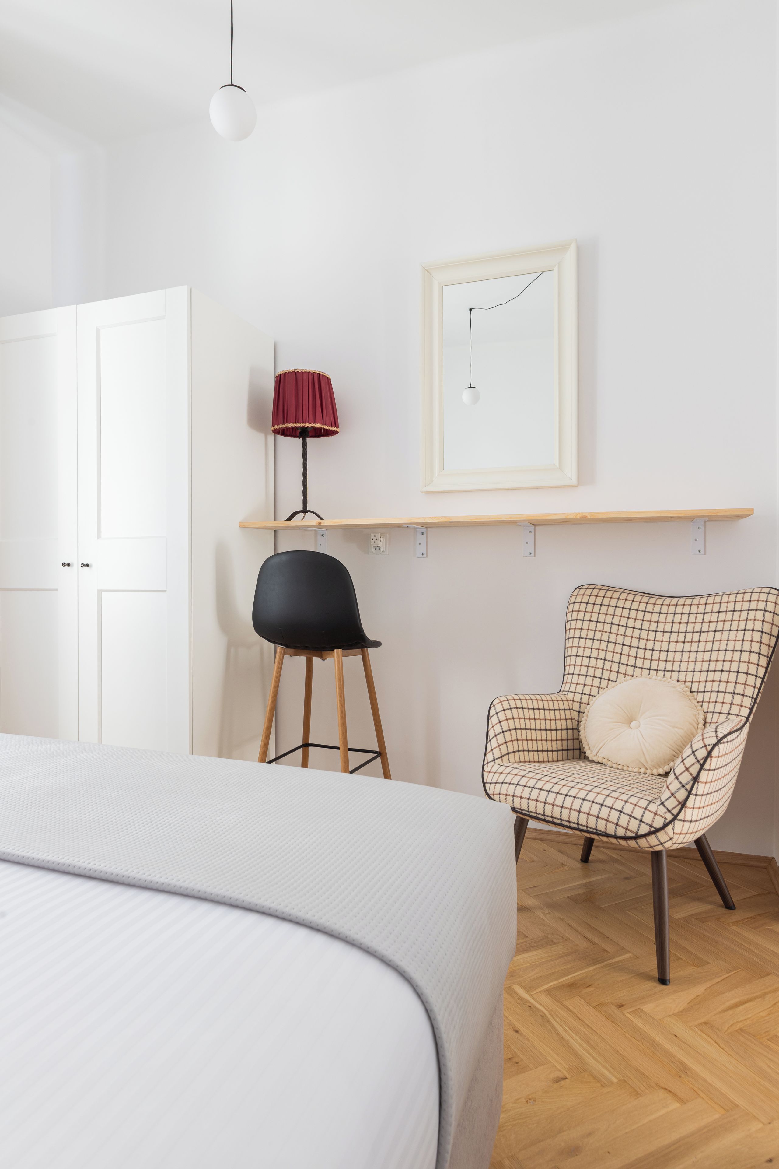 Une chambre à coucher avec un lit, une chaise, un bureau avec une lampe et un tableau au mur.
