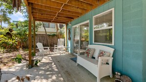 A covered patio with a white wicker sofa, white chairs, and a wooden ceiling. - Turtle Hideaway- Walk to Beach & Pier! (St. Augustine)