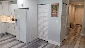 A modern kitchen with white cabinets, a built-in refrigerator, and a wooden floor.
