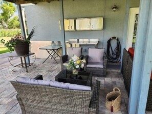 Relax in a serene outdoor space with wicker furniture, a small table, and a potted plant.