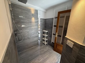 Une salle de bain moderne avec une douche à parois de verre, une étagère blanche et une porte en bois.