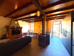 A spacious living area with a fireplace, a dining table, and a kitchen area. - Casa Claudia Pieve centro storico (Tremosine)