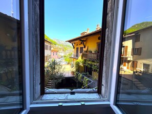 Une vue par la fenêtre sur une ville avec des bâtiments, une rue et une montagne en arrière-plan.