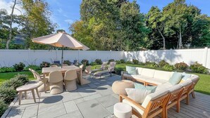 A patio with a round table, chairs, a sofa, and an umbrella.