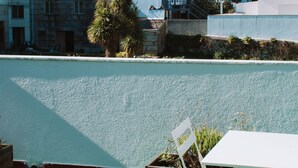A terrace with a view of buildings and a river. There are tables and chairs on the terrace. - ARCA NOVA GUEST HOUSE & HOSTEL (Caminha)