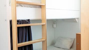 A bunk bed with a wooden ladder, a single bed below, and a small cabinet.