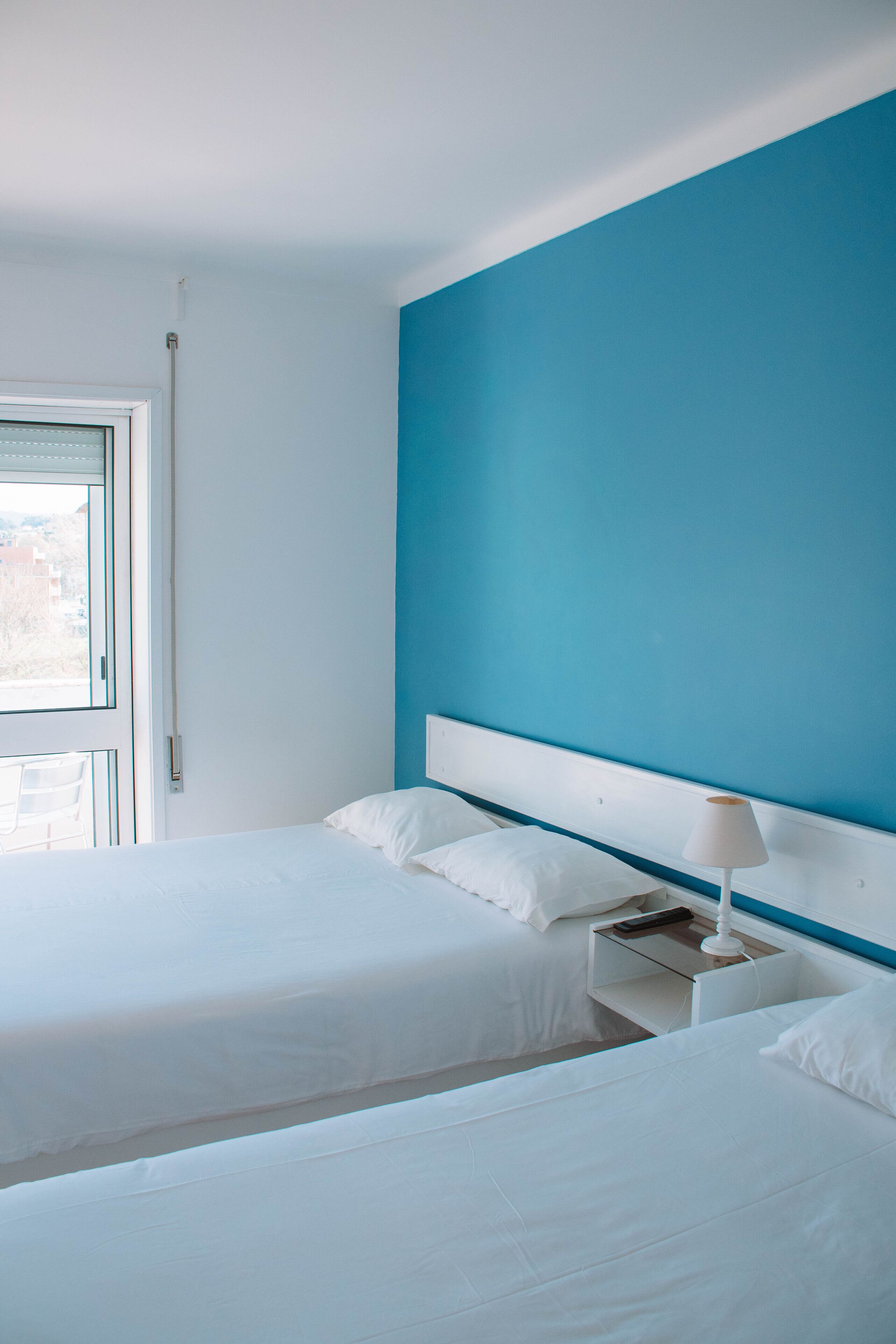 Une chambre d’hôtel avec deux lits, une fenêtre et une table de chevet avec une lampe.